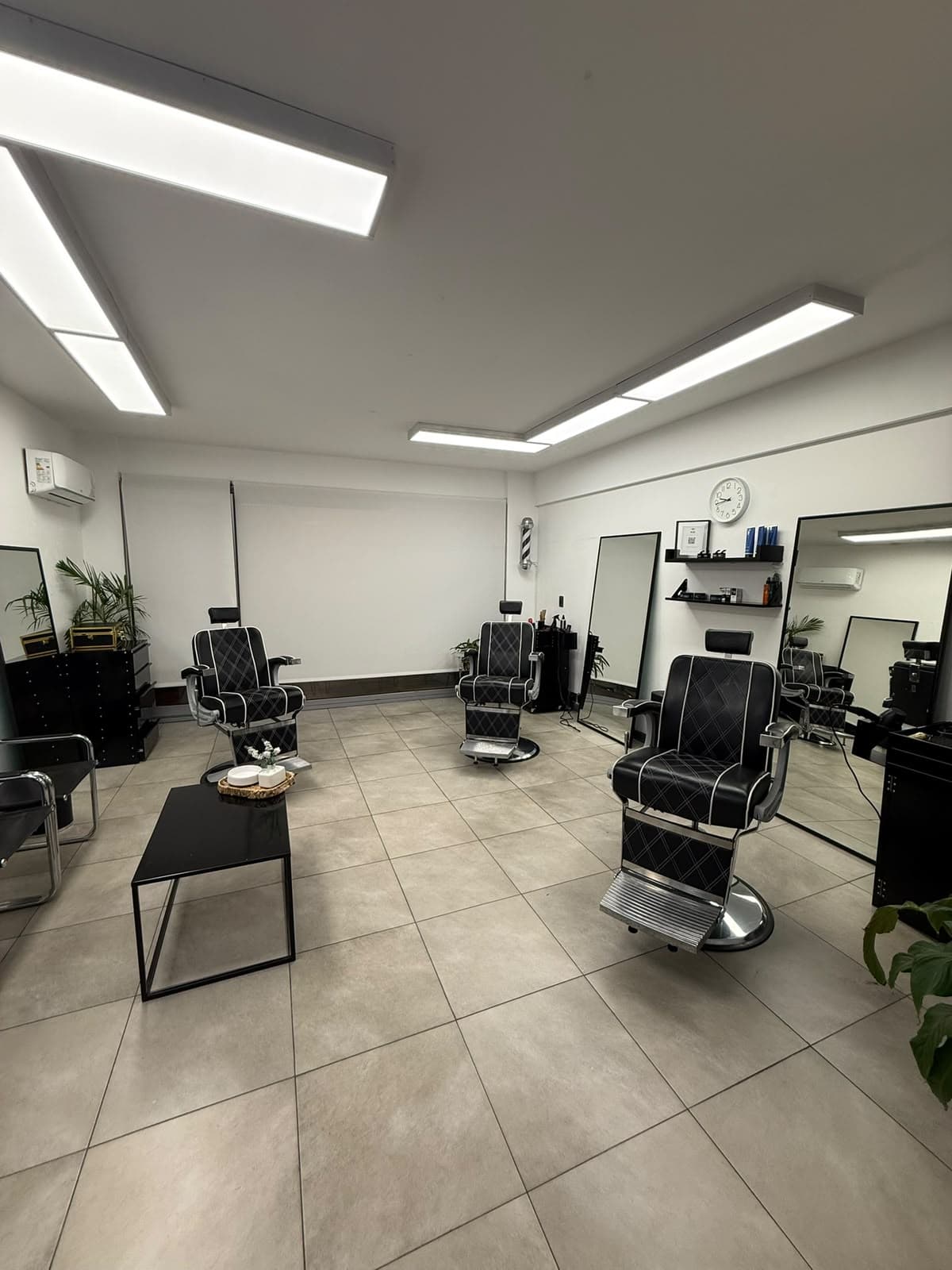 Sillones de barbero clásicos y espejos en el salón de AM Barbería, Villa Urquiza